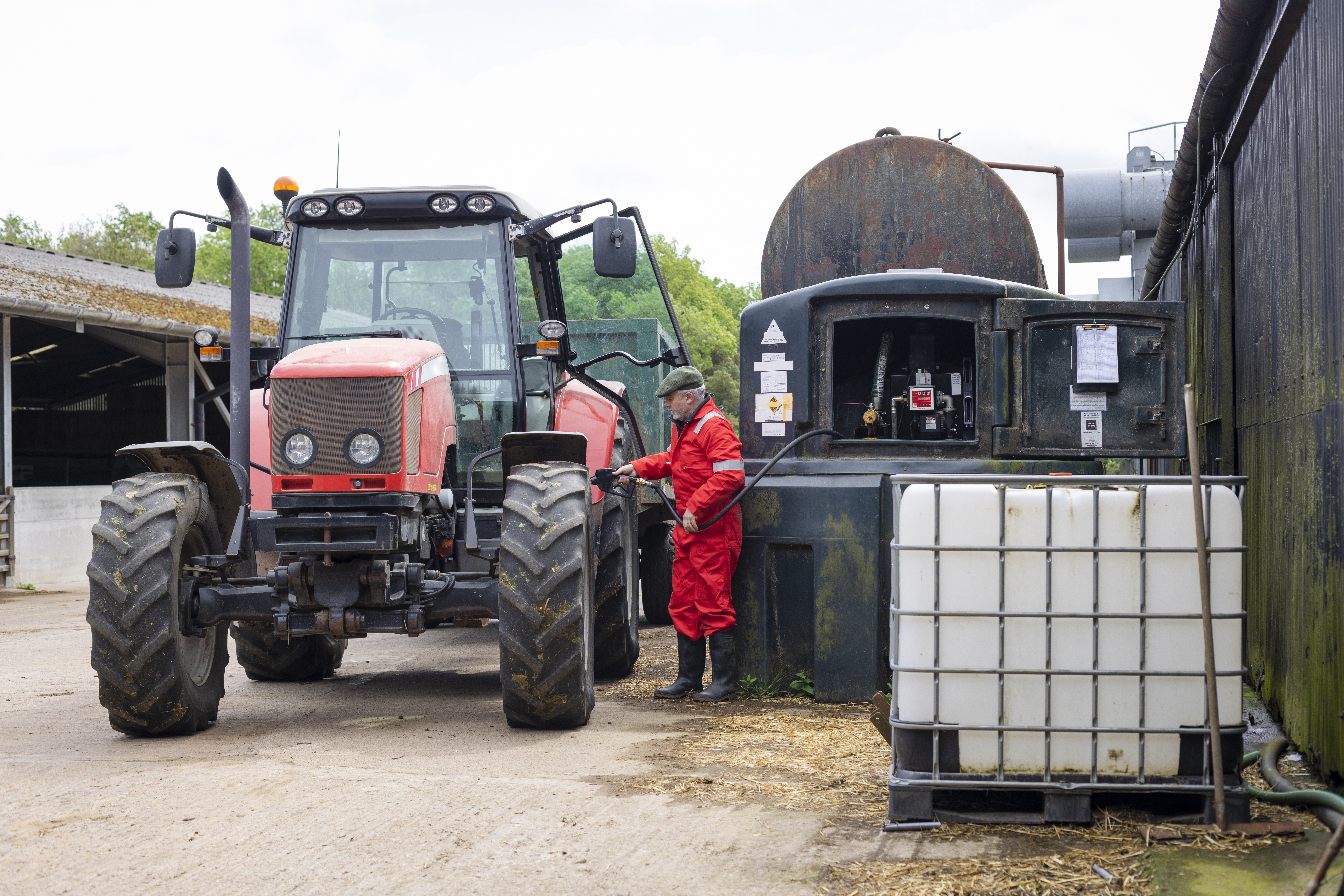 Farmer refuelling a tractor from a bulk fuel tank on a farm